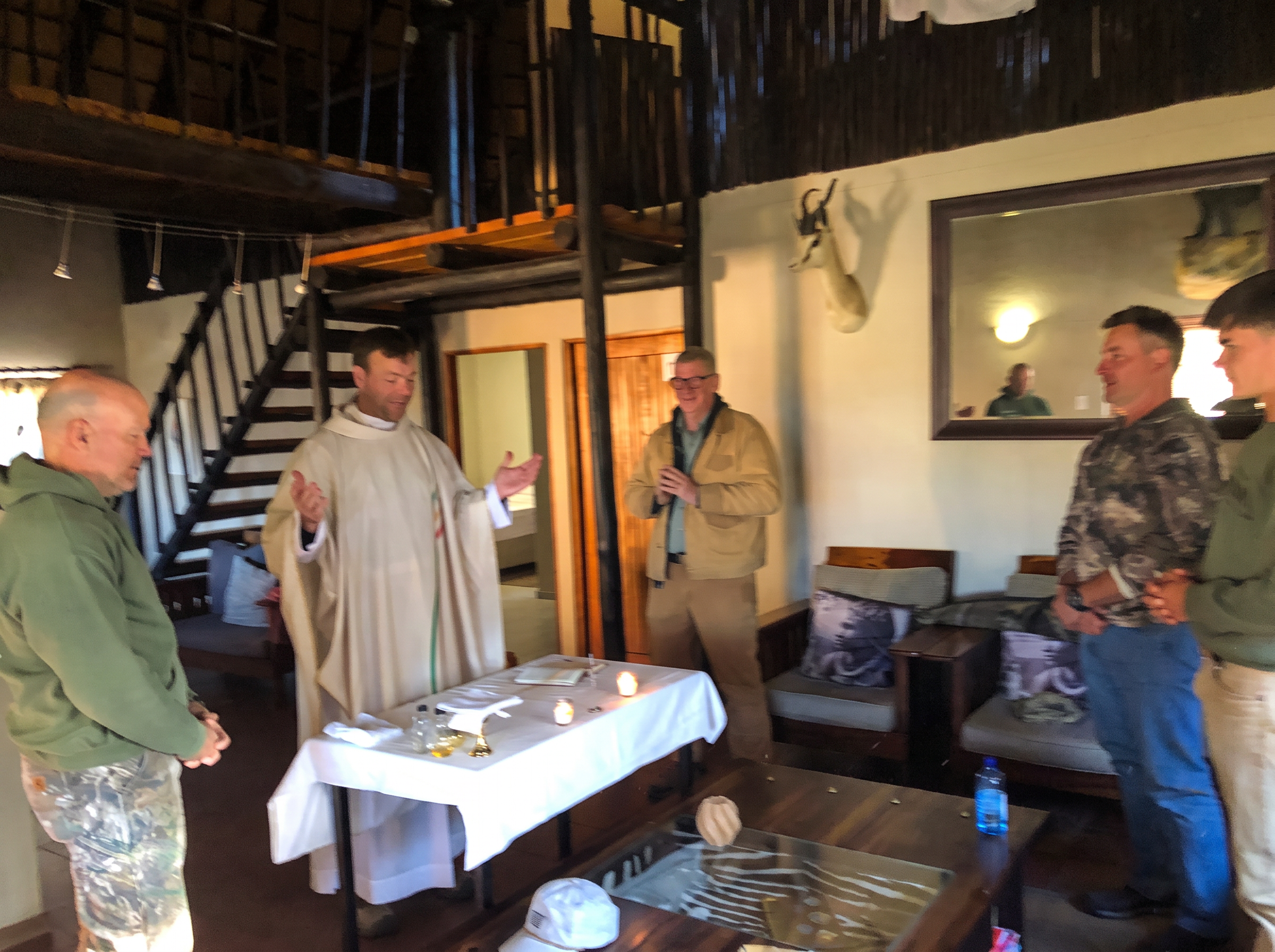 A priest celebrating Holy Mass on a lodge table while retreat men stand in prayer around him